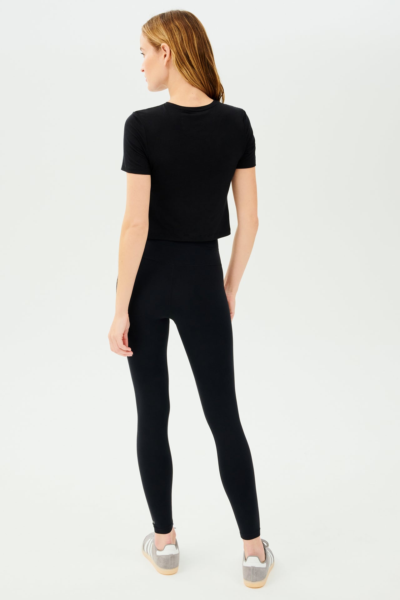 The back view of a woman wearing SPLITS59 Daisy Jersey Tee - Black leggings.