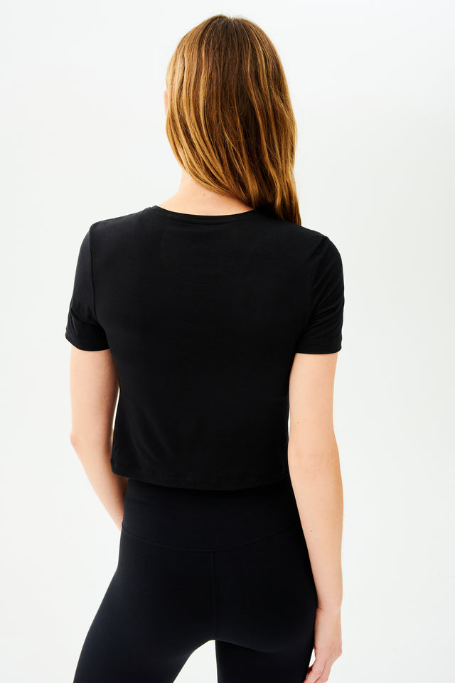 The back view of a woman wearing high waist leggings and a SPLITS59 Daisy Jersey Tee in Black.
