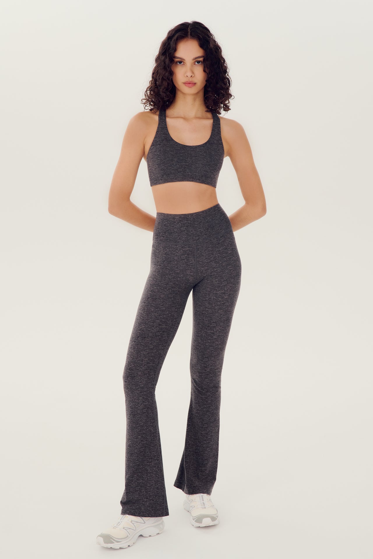 The model is wearing a grey crop top and Raquel High Waist Airweight Flare leggings in Heather Grey by SPLITS59, perfect for Pilates.