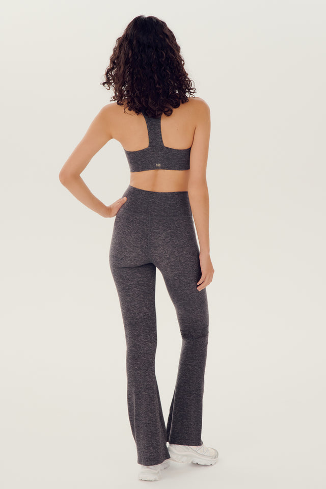 The back view of a woman wearing SPLITS59 Raquel High Waist Airweight Flare - Heather Grey leggings.