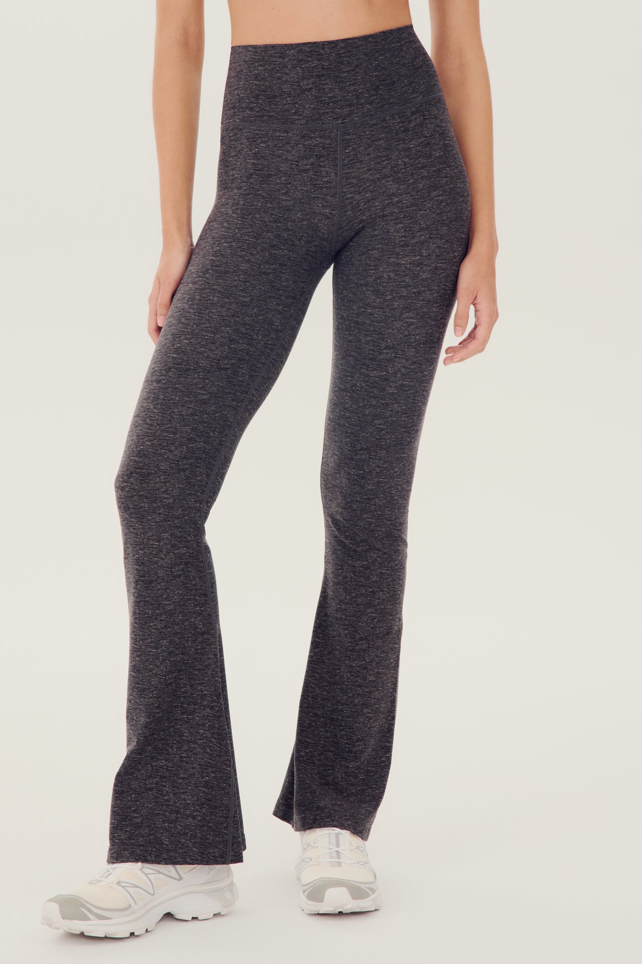 A woman wearing grey SPLITS59 Raquel High Waist Airweight Flare leggings and a white top.