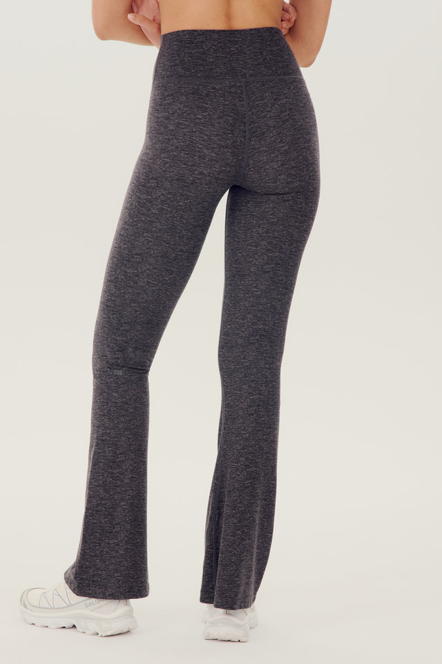 The back view of a woman wearing SPLITS59's Raquel High Waist Airweight Flare - Heather Grey leggings.