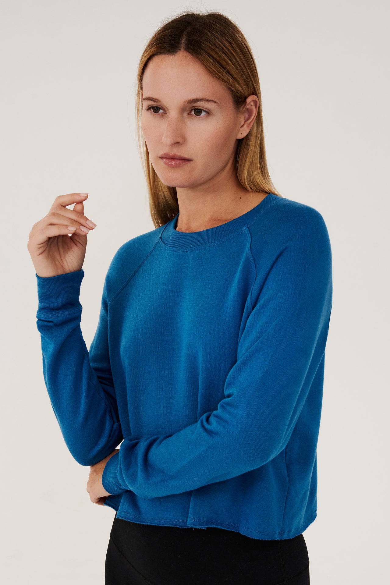Front view of woman with dark blonde hair, wearing  bright cropped blue sweatshirt with black leggings