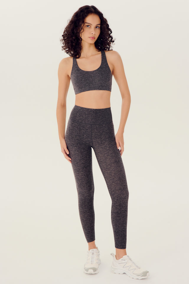 Full front view of girl wearing highwasited grey leggings with grey sports bra and white shoes
