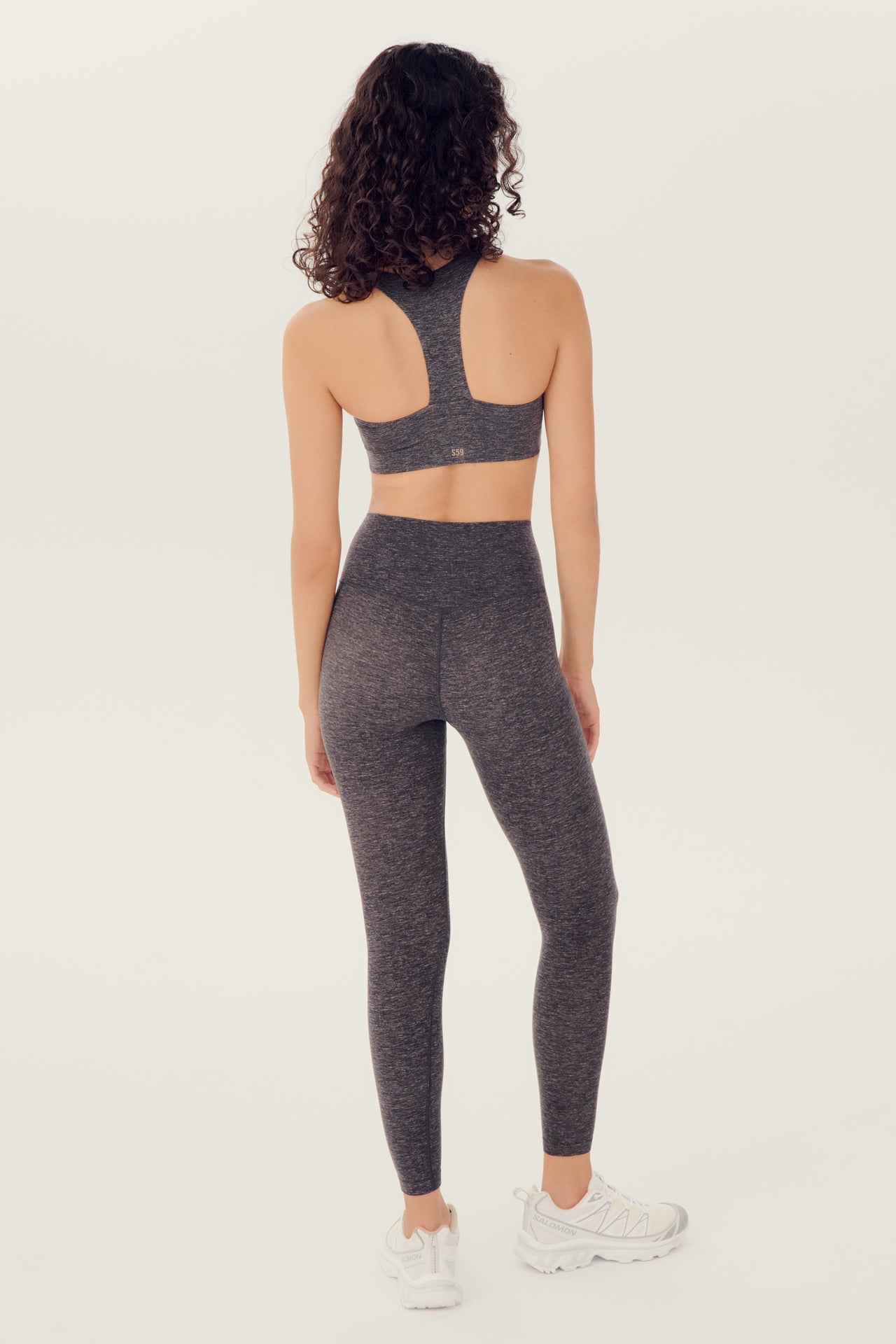 Full back view of girl wearing highwasited grey leggings with grey sports bra and white shoes