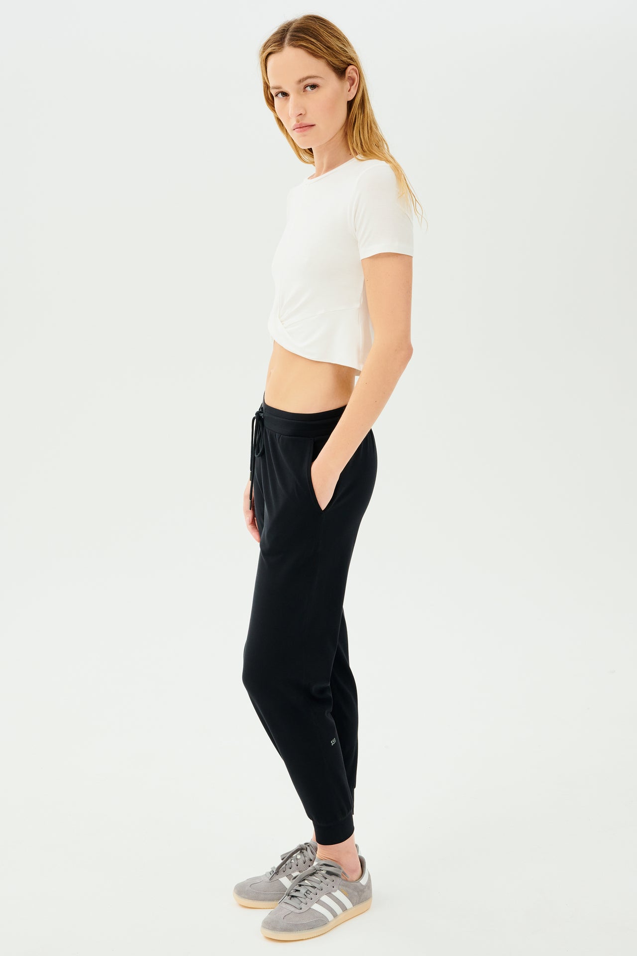 A woman wearing a flirty Daisy Jersey Tee in white from SPLITS59 and black high waist leggings.
