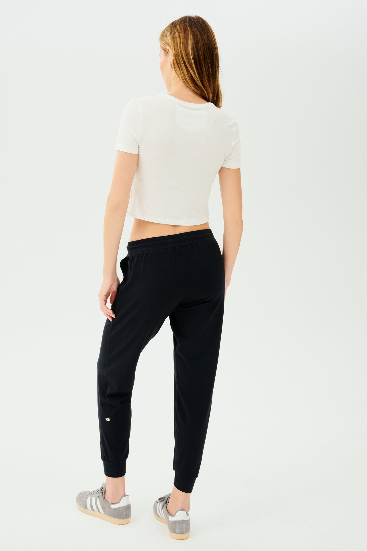The back view of a woman wearing black high waist leggings and a Daisy Jersey Tee - White by SPLITS59.