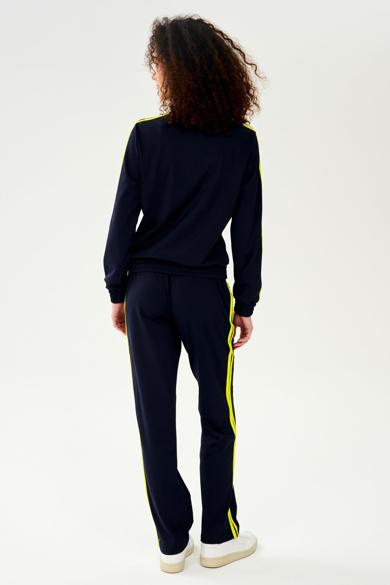 The back view of a woman wearing a SPLITS59 Fox Techflex Jacket in Indigo/Chartreuse.