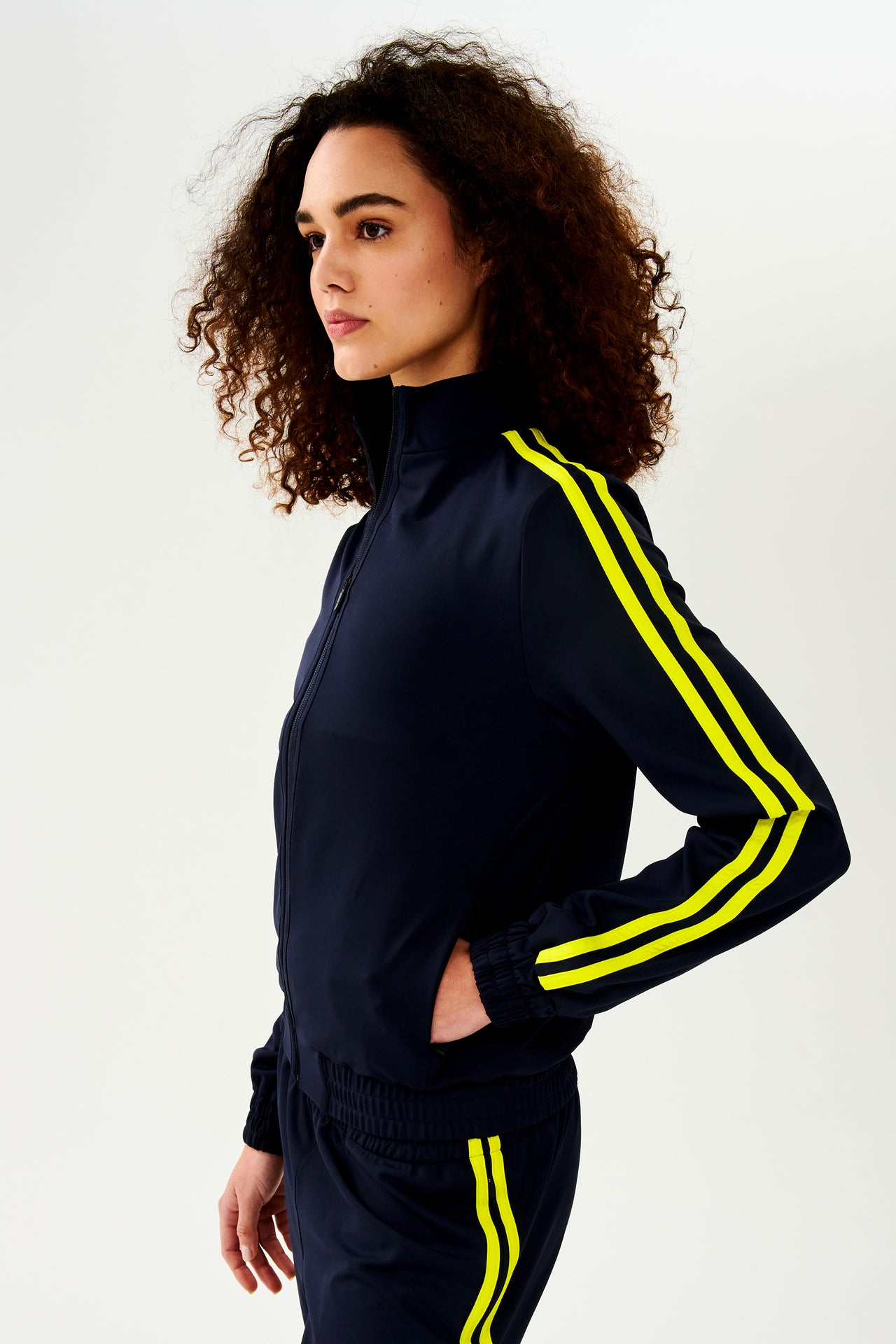 A woman wearing a luxurious Fox Techflex Jacket in Indigo/Chartreuse, ideal as an après workout piece by SPLITS59.