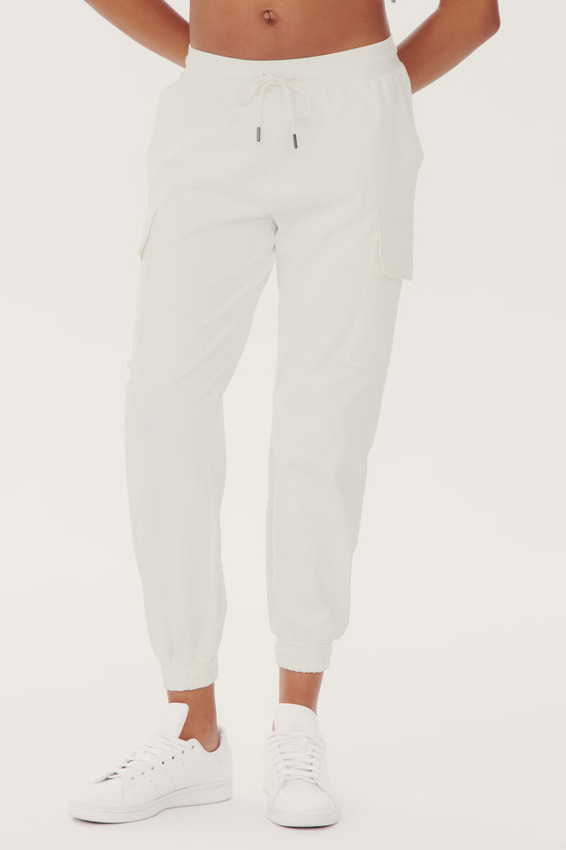 A person wearing white Supplex Cargo Pant - White from SPLITS59 and white sneakers against a plain background. Only the lower half of the body is visible.