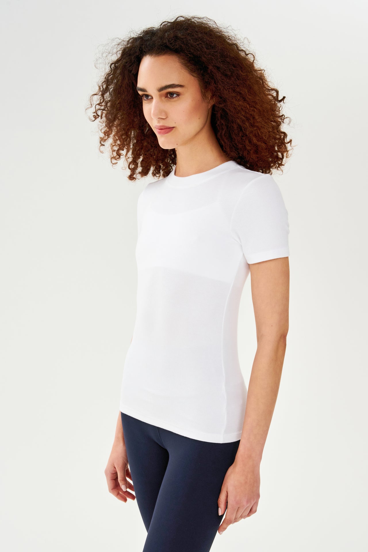 A woman wearing a SPLITS59 Louise Rib Short Sleeve - White t-shirt and leggings for yoga.
