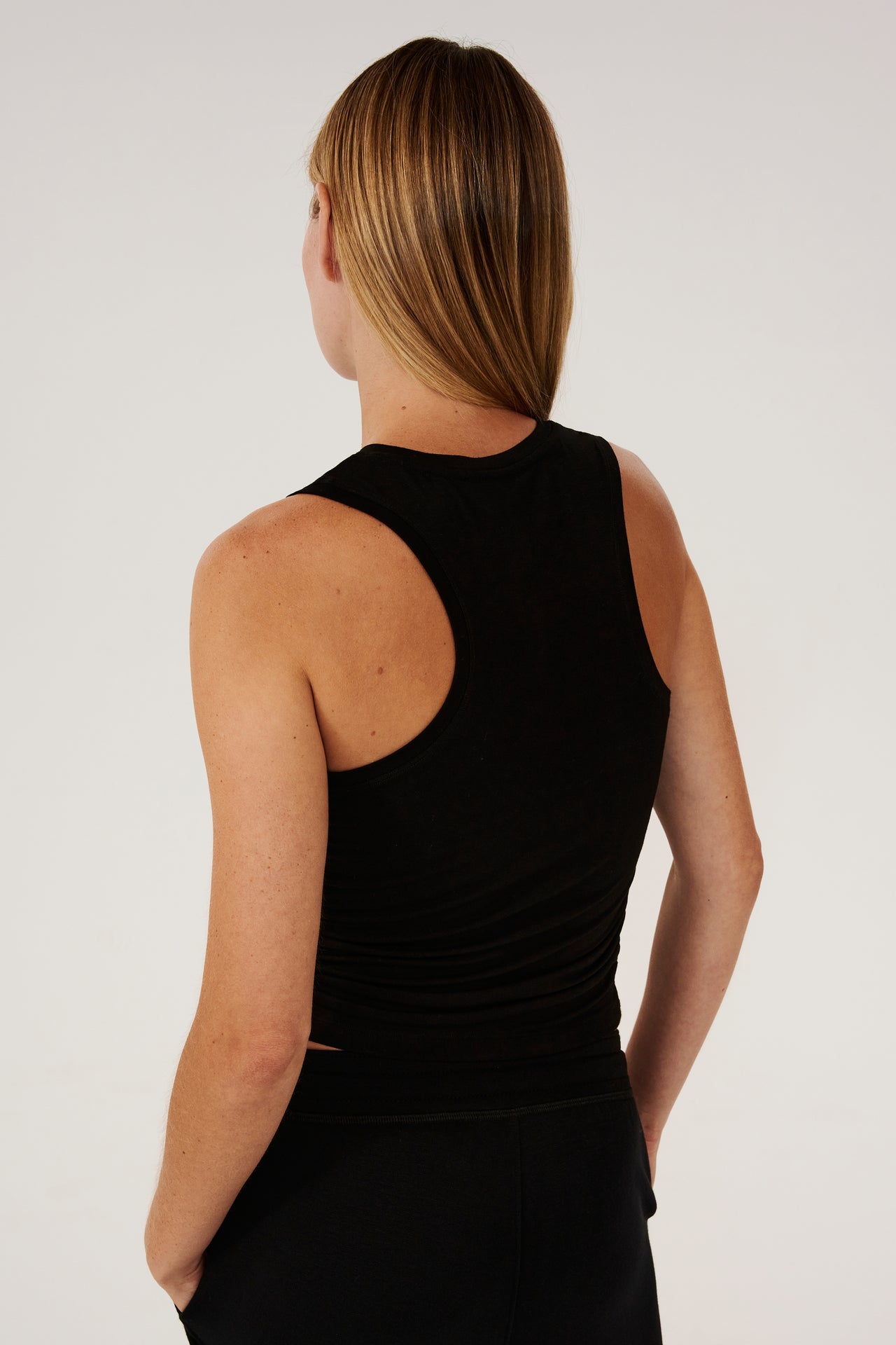 The back view of a woman wearing Frida Jersey Tank in Black by SPLITS59, ideal for gym workouts.