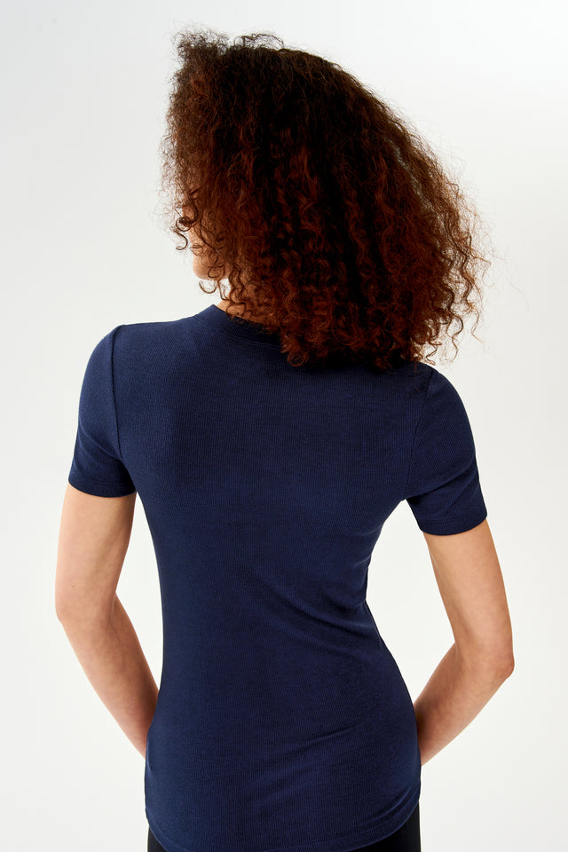 The back of a woman wearing a SPLITS59 Louise Rib Short Sleeve - Indigo t-shirt during her gym workouts.