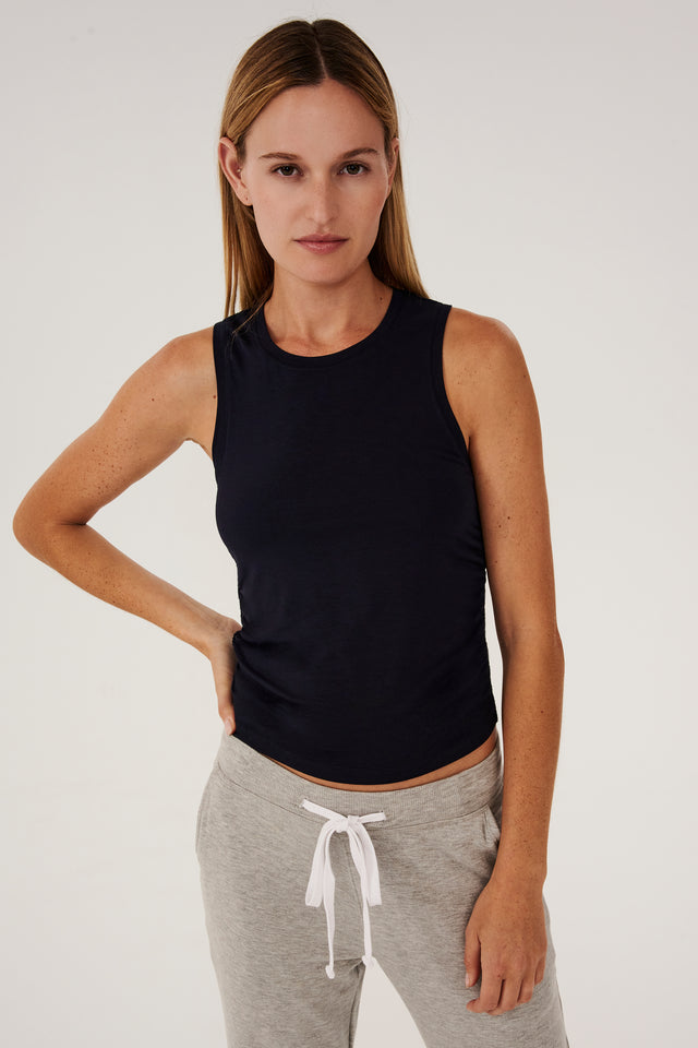 The model is wearing a black Frida Jersey Tank - Indigo and grey sweatpants, perfect for gym workouts by SPLITS59.
