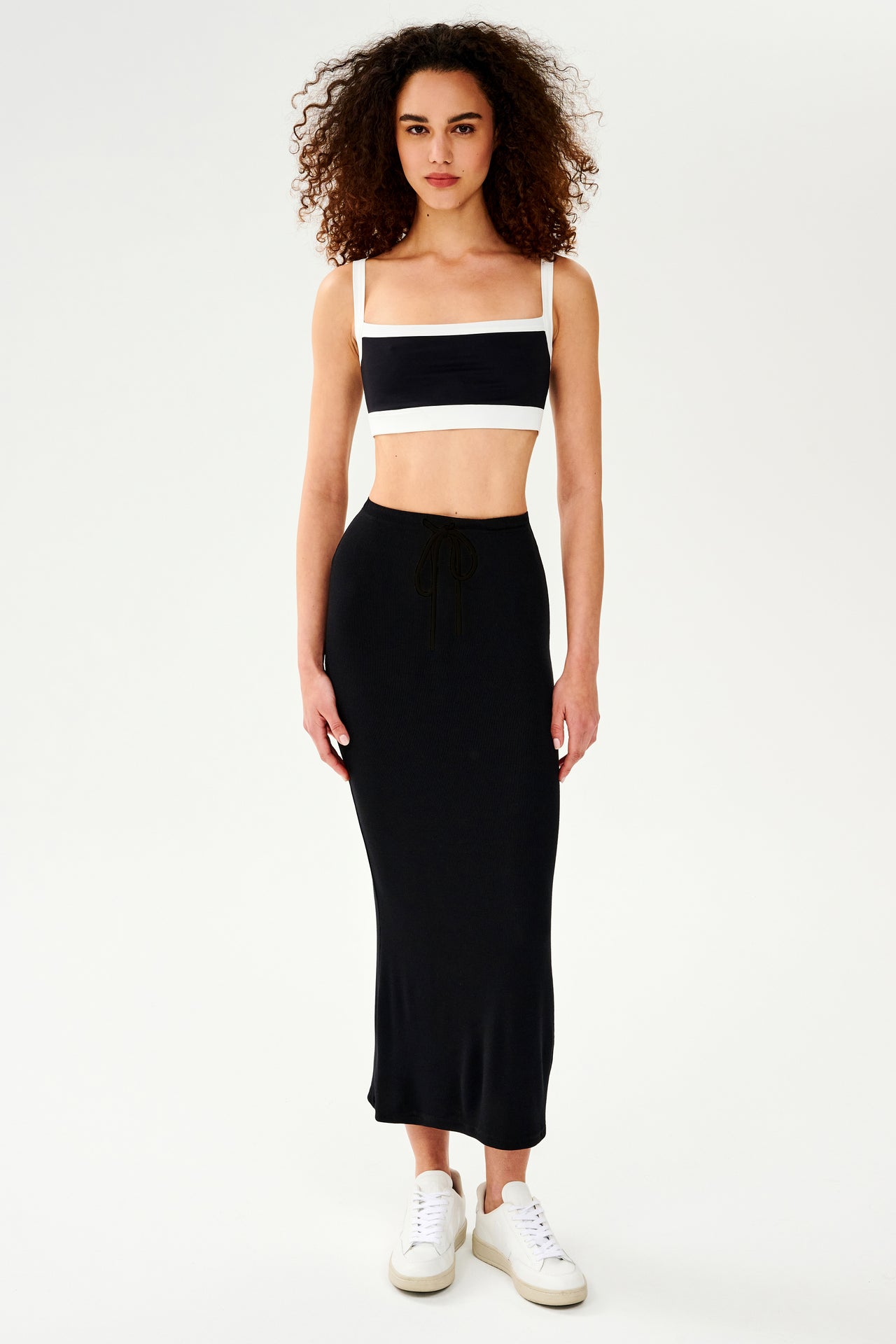 The model is wearing a black and white crop top and SPLITS59 Kiki Rib Maxi Skirt - Black, perfect for lounging at home.