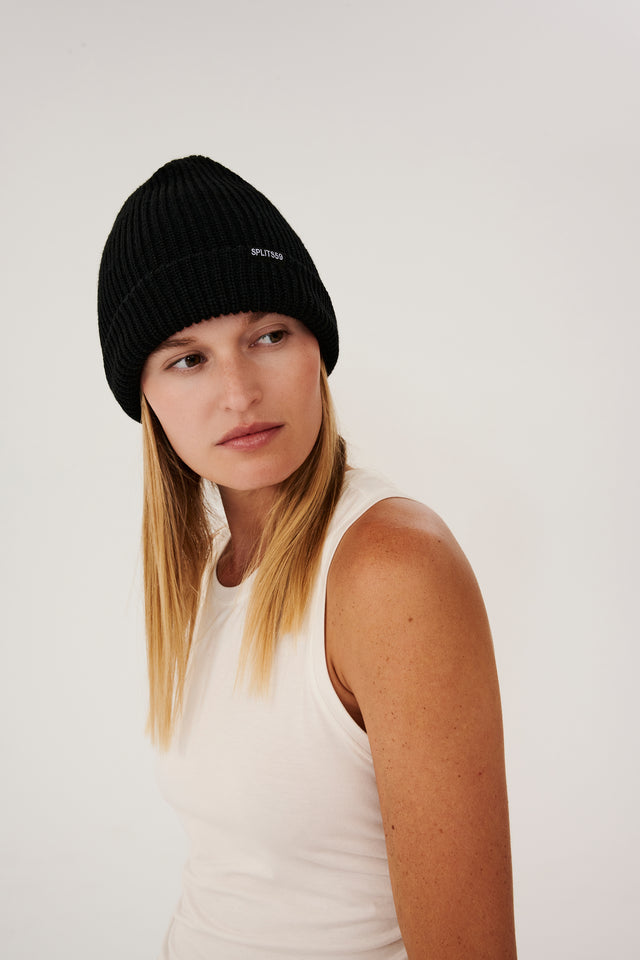 Front view of a girl in a black beanie with splits 59 logo and a white tank top