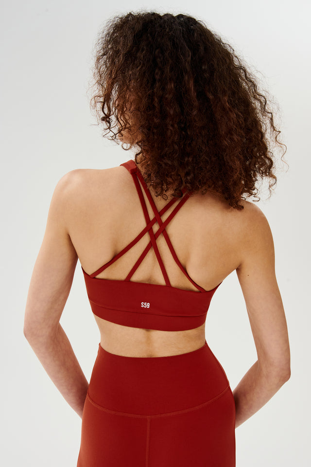 Back view of girl wearing red 4 criss crossed spaghetti straps sports bra