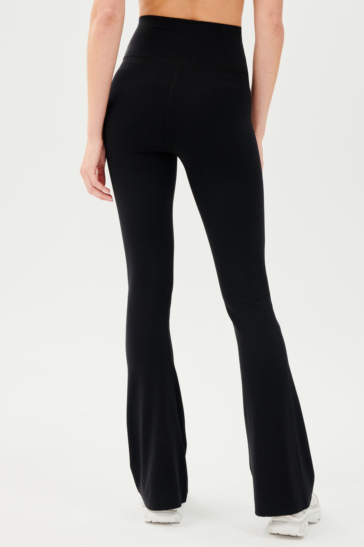 The back view of a woman wearing SPLITS59's Raquel High Waist Airweight Flare - Black leggings.