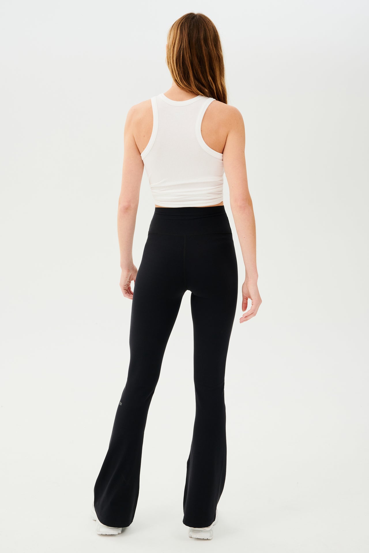 The back view of a woman wearing Raquel High Waist Airweight Flare - Black leggings made of SPLITS59 fabric.