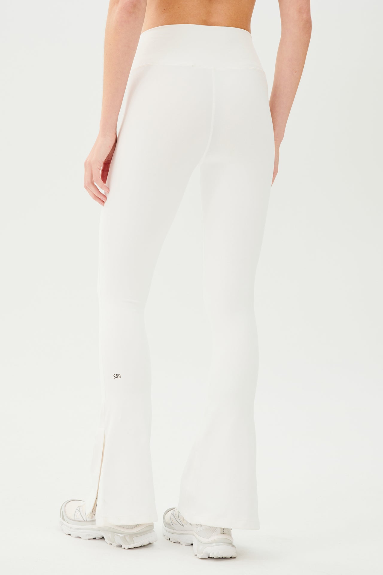 The back view of a woman wearing SPLITS59 Raquel High Waist Flare w/ Split Hem - White leggings made from 4-way stretch fabric.