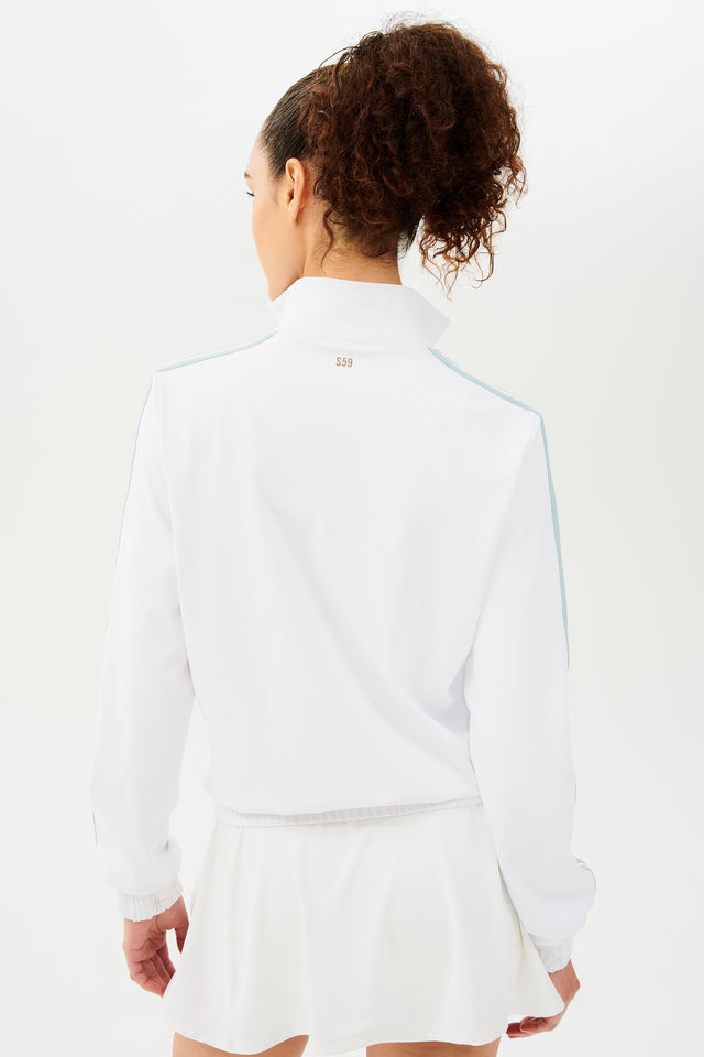 The back view of a woman wearing a SPLITS59 Fox Techflex Jacket in White/Teal with a retro vibe.