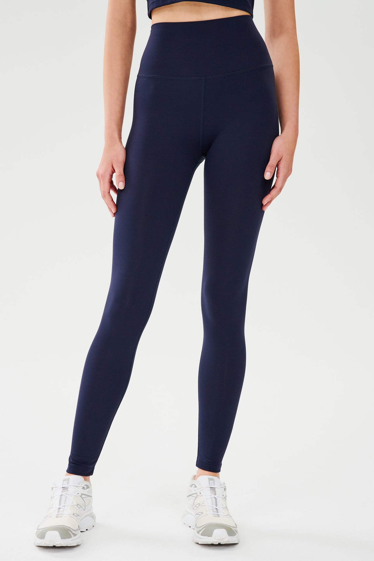 Front view of model wearing dark blue high waist  leggings  with white shoes 