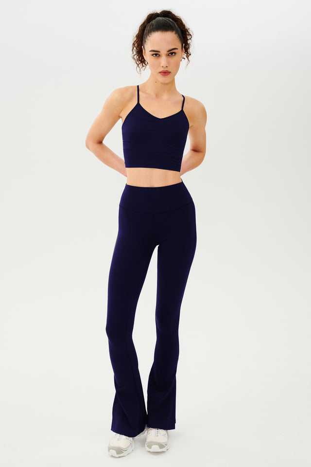 The model is wearing SPLITS59's Raquel High Waist Flare w/ Split Hem - Indigo top and leggings, both featuring a 4-way stretch perfect for workout activities.