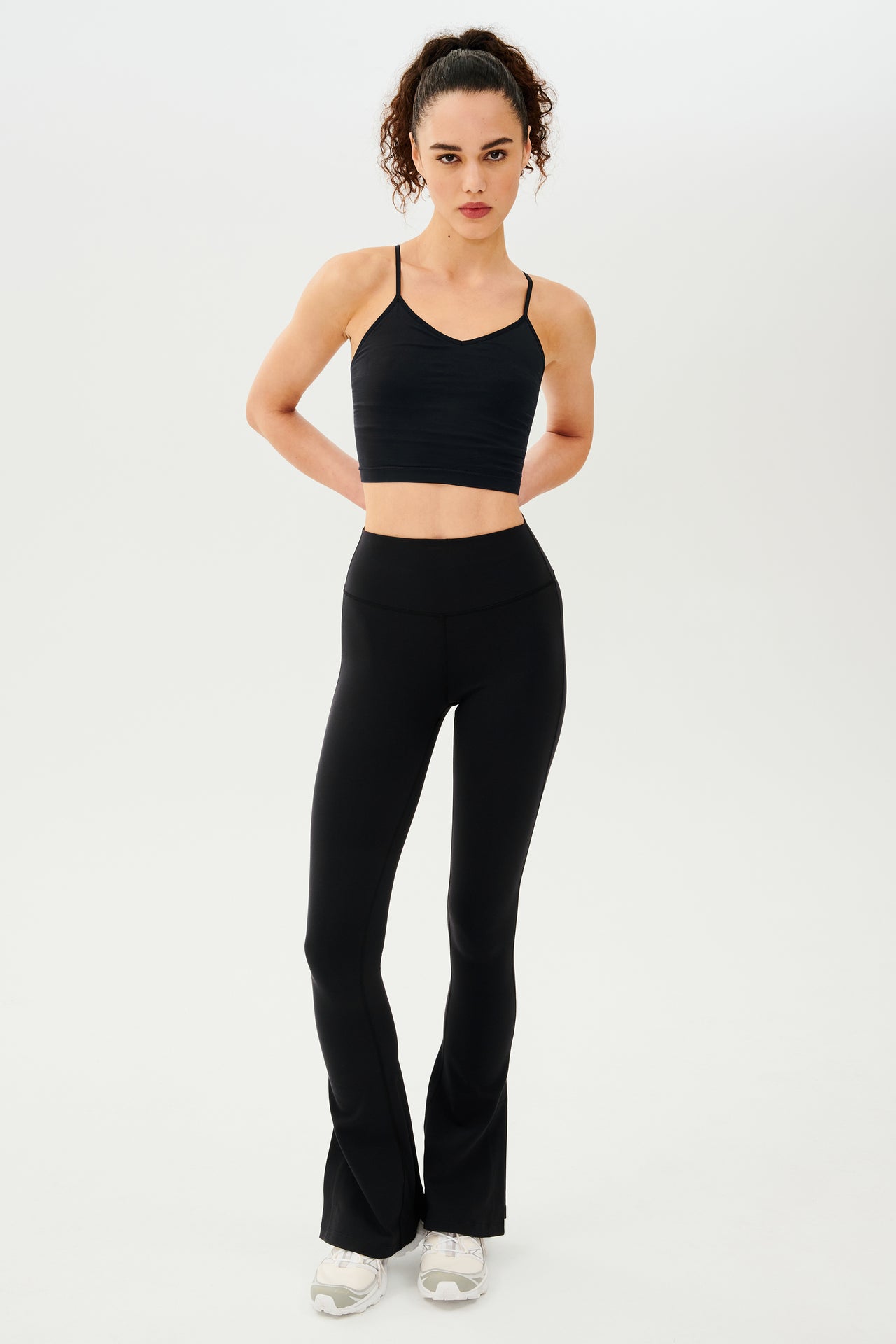 A woman wearing Raquel High Waist Flare w/ Split Hem - Black leggings and a black crop top made from 4-way stretch supplex fabric, perfect for gym workouts.