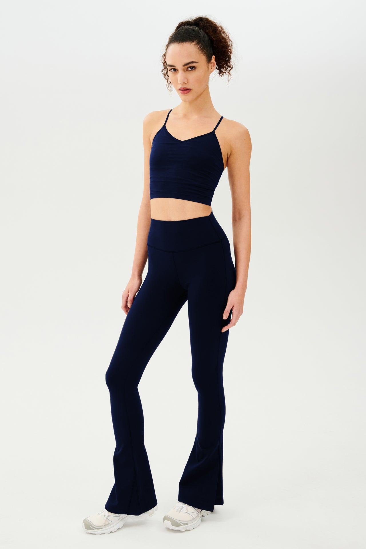 The model is wearing a navy crop top and SPLITS59 Raquel High Waist Flare w/ Split Hem - Indigo leggings.