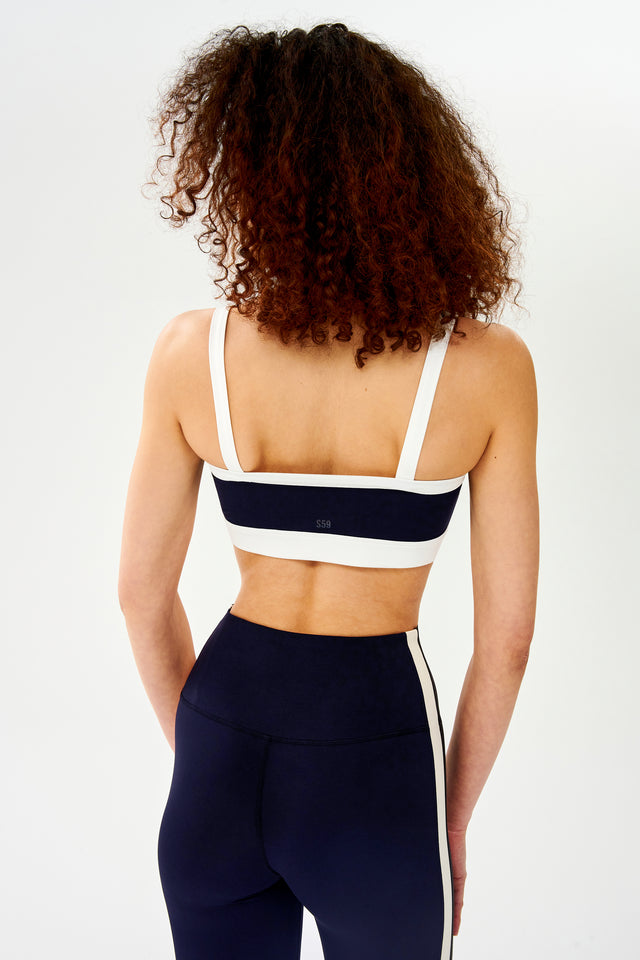 The back view of a woman wearing a SPLITS59 Monah Rigor Bra styled in a retro sport vibe.