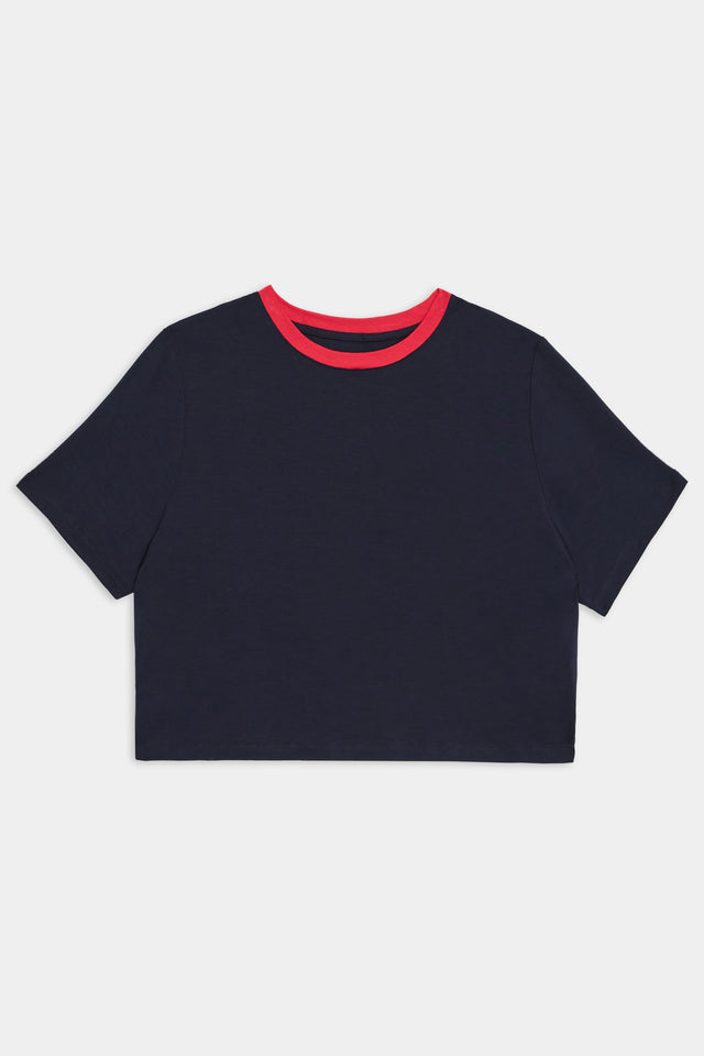 Navy blue short-sleeve crop top with a red crew neck collar, perfect for gym workouts or outdoor workouts, displayed on a white background. The product is the Djuna Crop Ringer - Indigo/Pirate Red from SPLITS59.