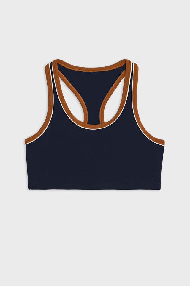 Front flat view of dark blue bra with white and dark orange border arm and neckline and racerback and dark blue leggings with dark orange double side stripes.