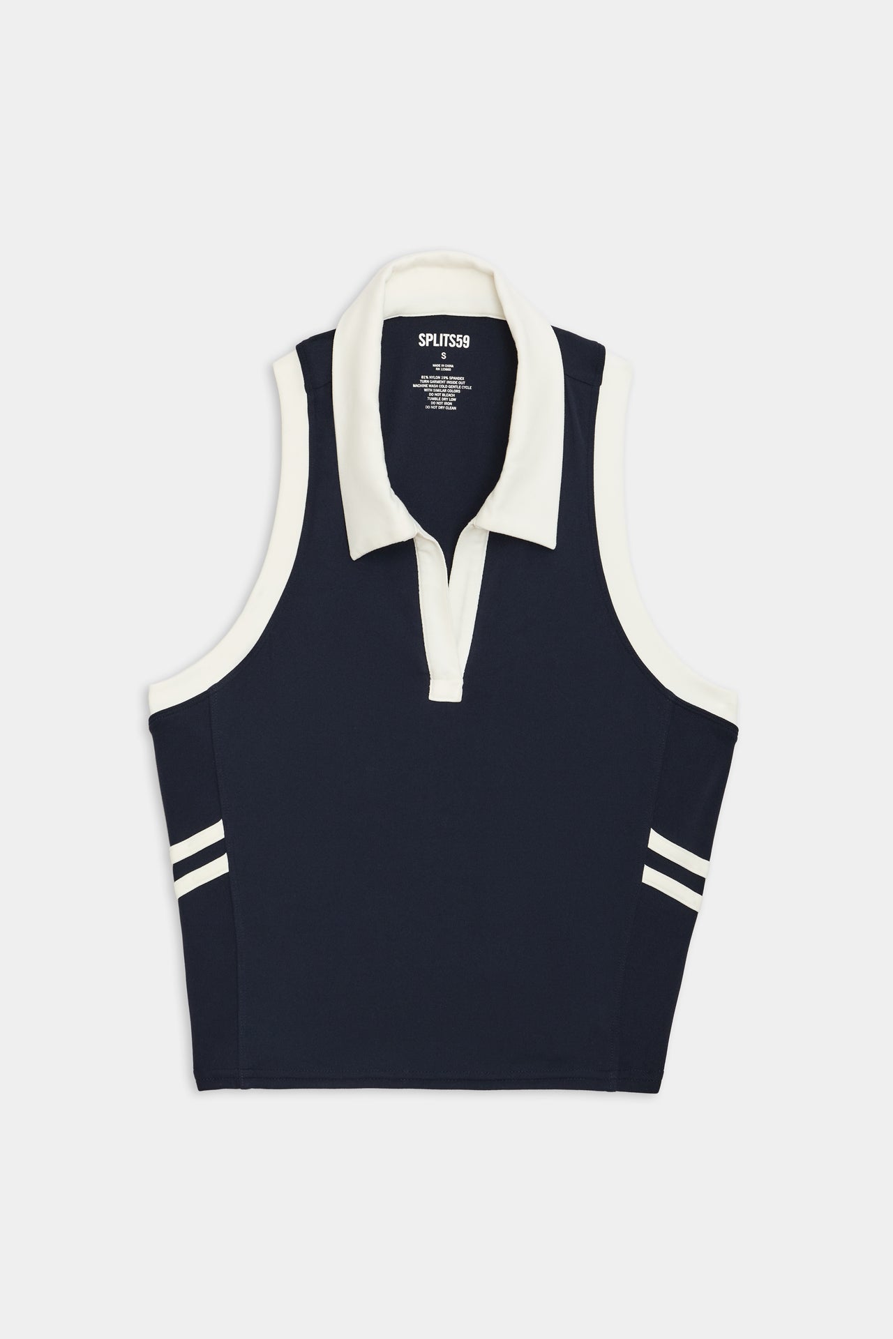 Austin Airweight Crop Polo - Indigo/White by SPLITS59, a navy blue and white sleeveless collared shirt made of nylon spandex fabric, with stripe details on the shoulders, displayed against a white background.