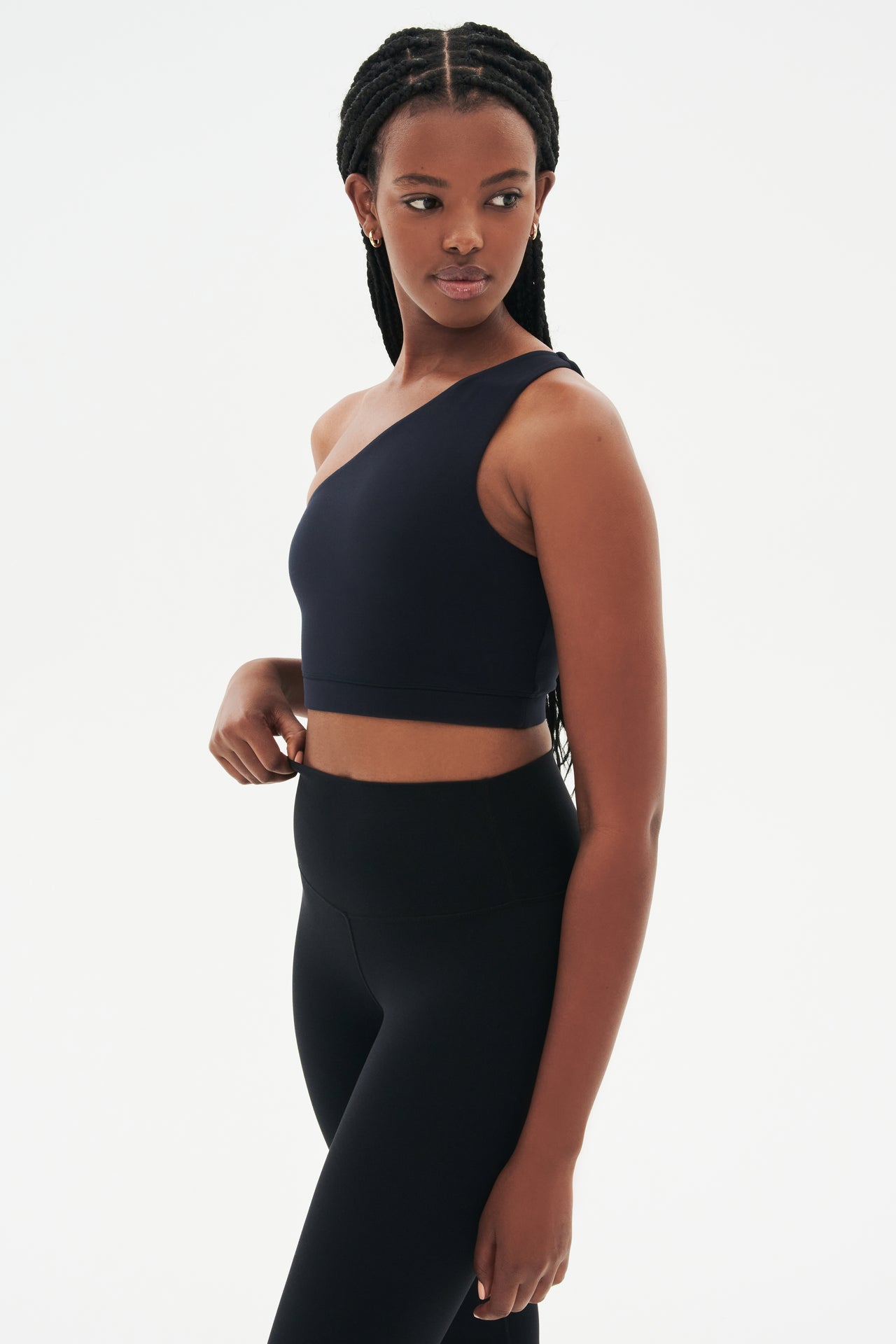Side view of girl wearing a black one shoulder bra and a black leggings 