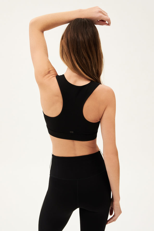 Back view of girl wearing black square neck sports bra and black leggings