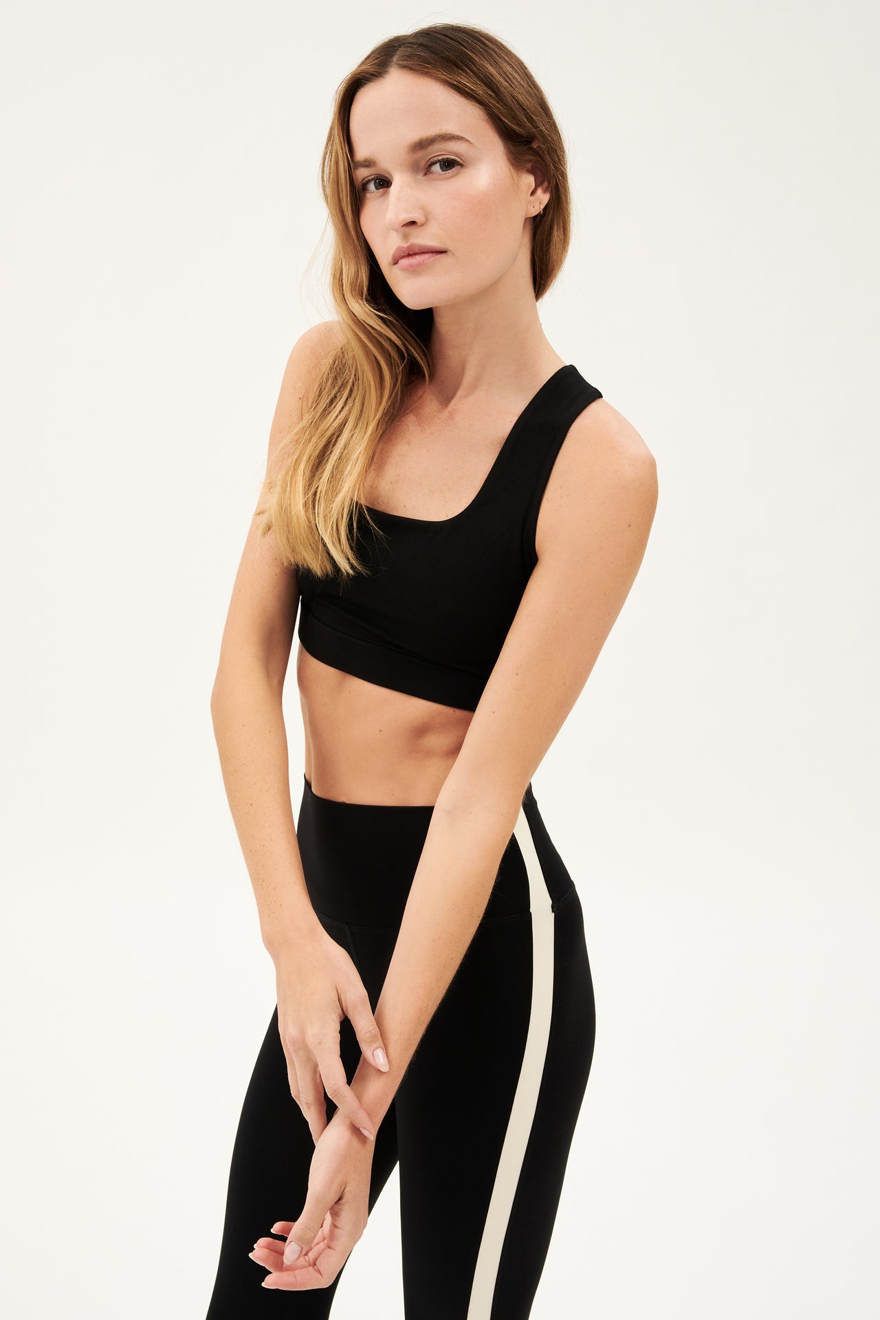 Side view of girl wearing black square neck sports bra and black leggings