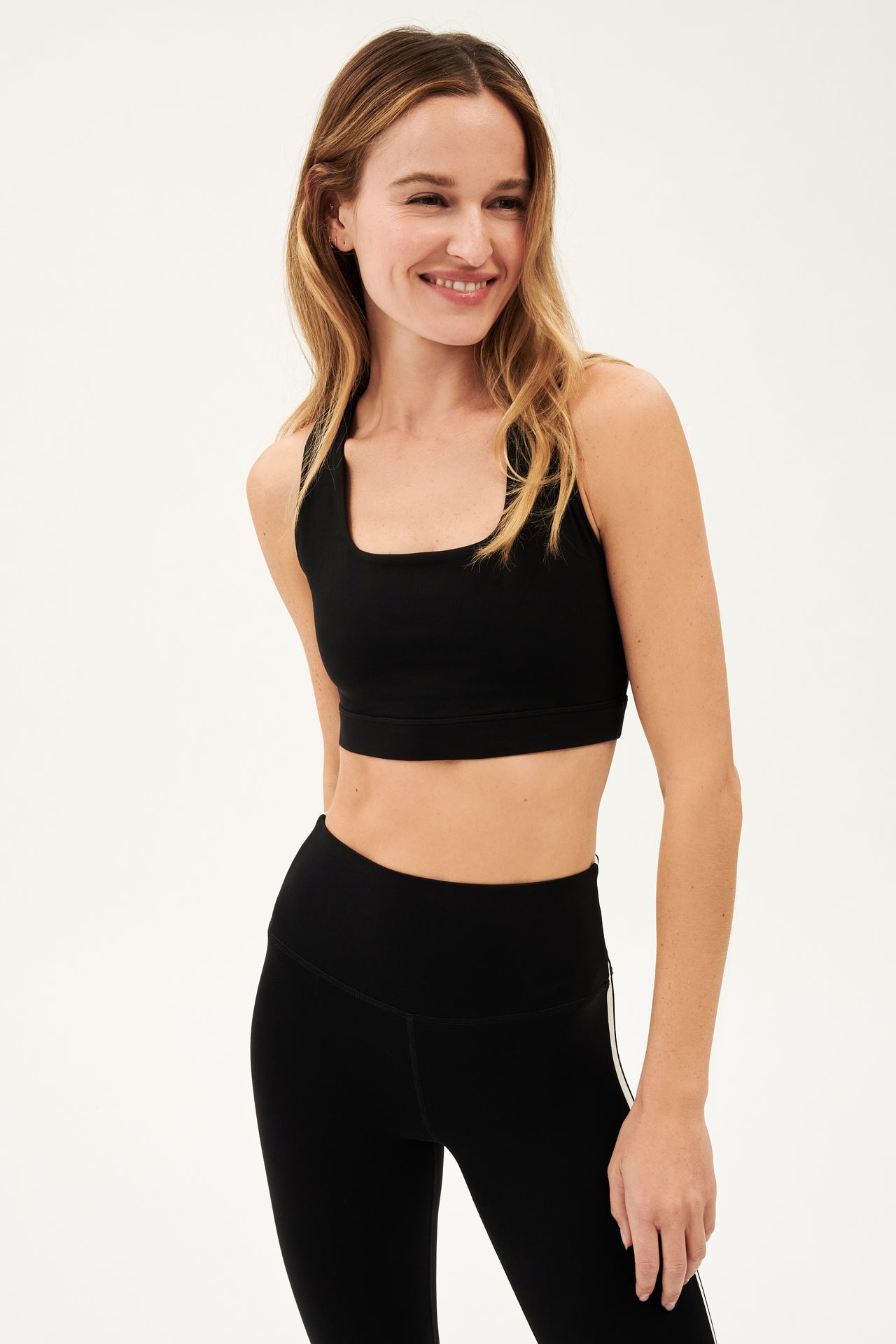 Front view of girl wearing black square neck sports bra and black leggings 