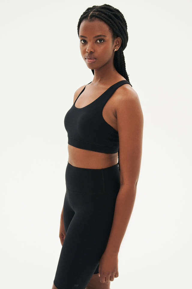 Side view of girl wearing black sports bra and black high waisted bike shorts 