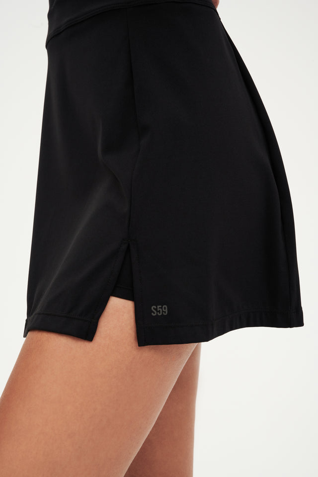 The back of a woman wearing a black SPLITS59 Martina Rigor Dress tennis skirt.