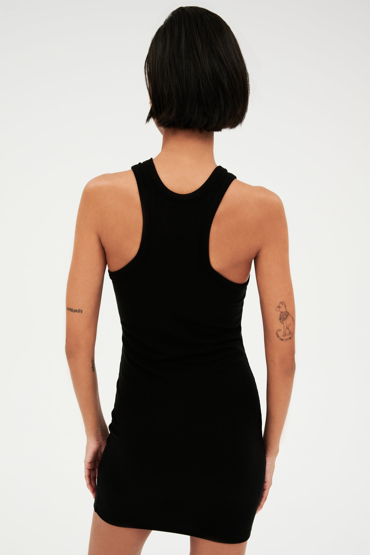 The back view of a woman wearing a SPLITS59 Kiki Rib Dress in Black perfect for summer.