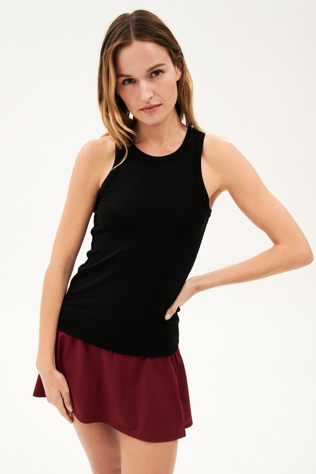 Full front view of woman with dark blonde hair wearing a blank tank top and dark red skort