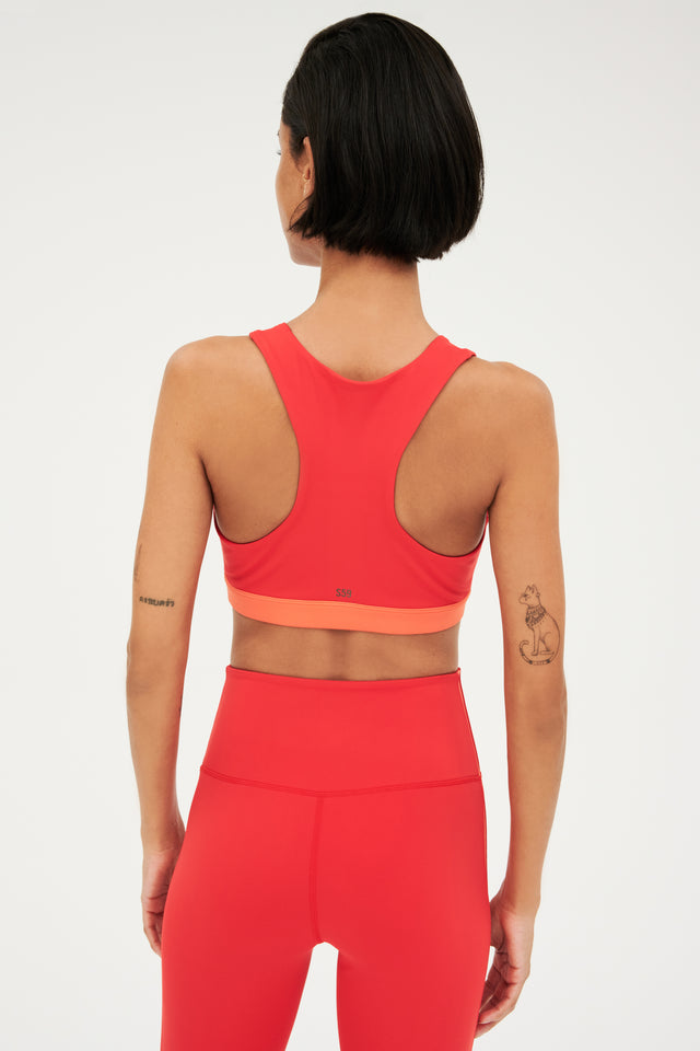 Back view of girl wearing red with a orange band around the ribs and red leggings 