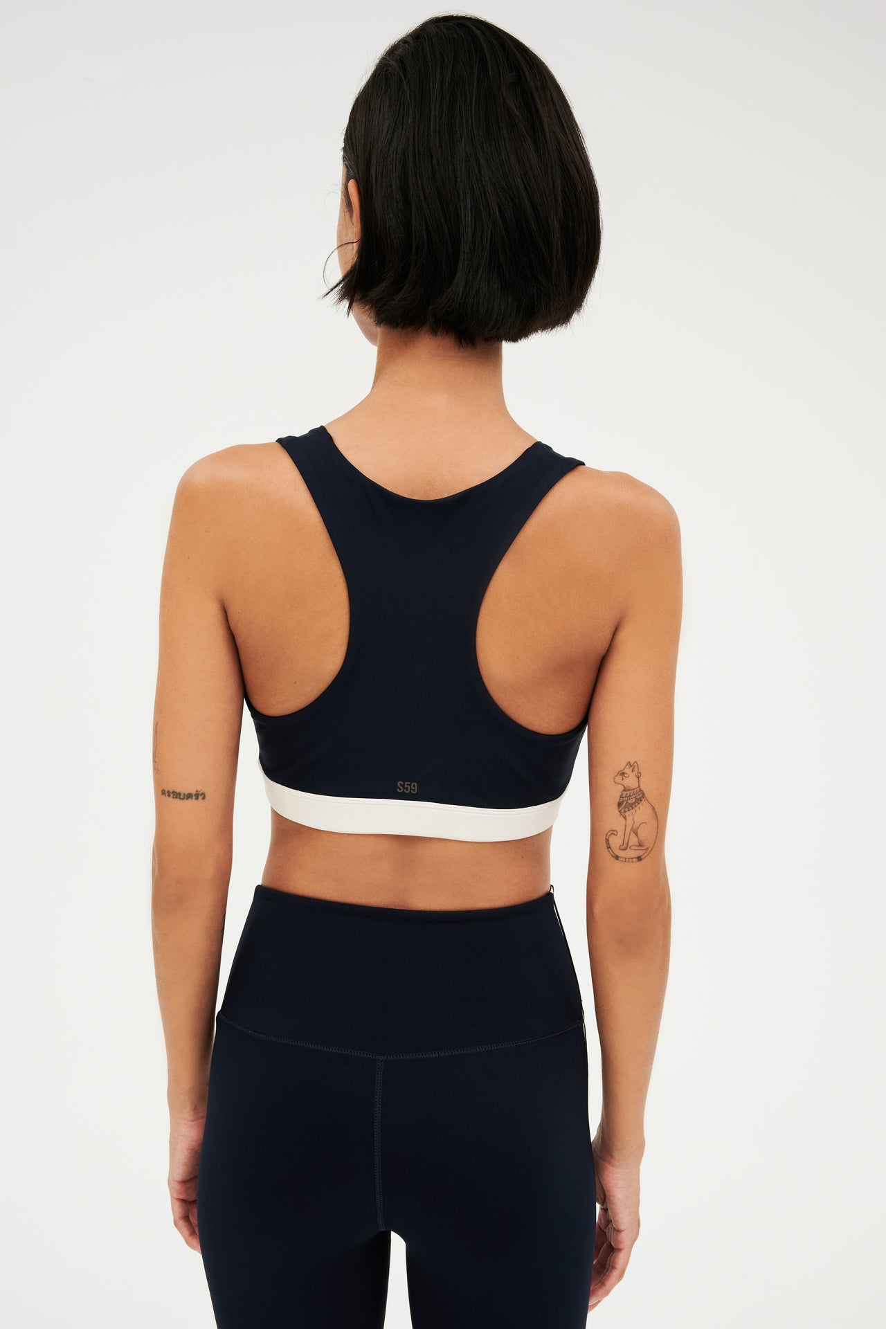 Back view of girl wearing dark blue with a white band around the ribs and dark blue leggings 