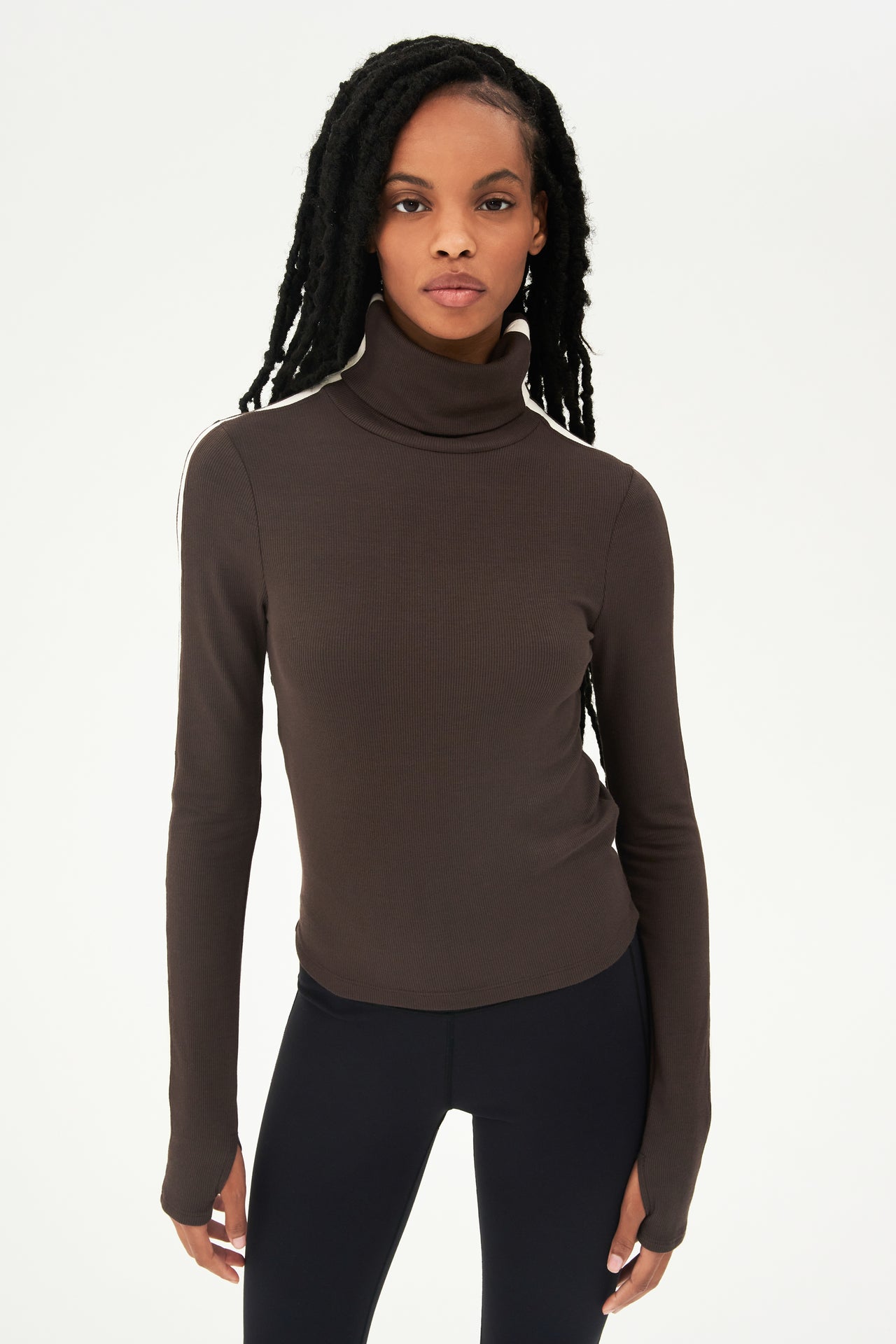 A woman wearing a SPLITS59 Jackson Rib Turtleneck in Dark Chocolate/Creme and black leggings.