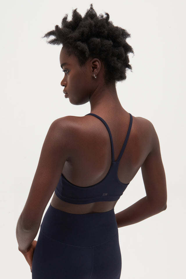 Back view of girl wearing dark blue spaghetti strap bra and blue leggings