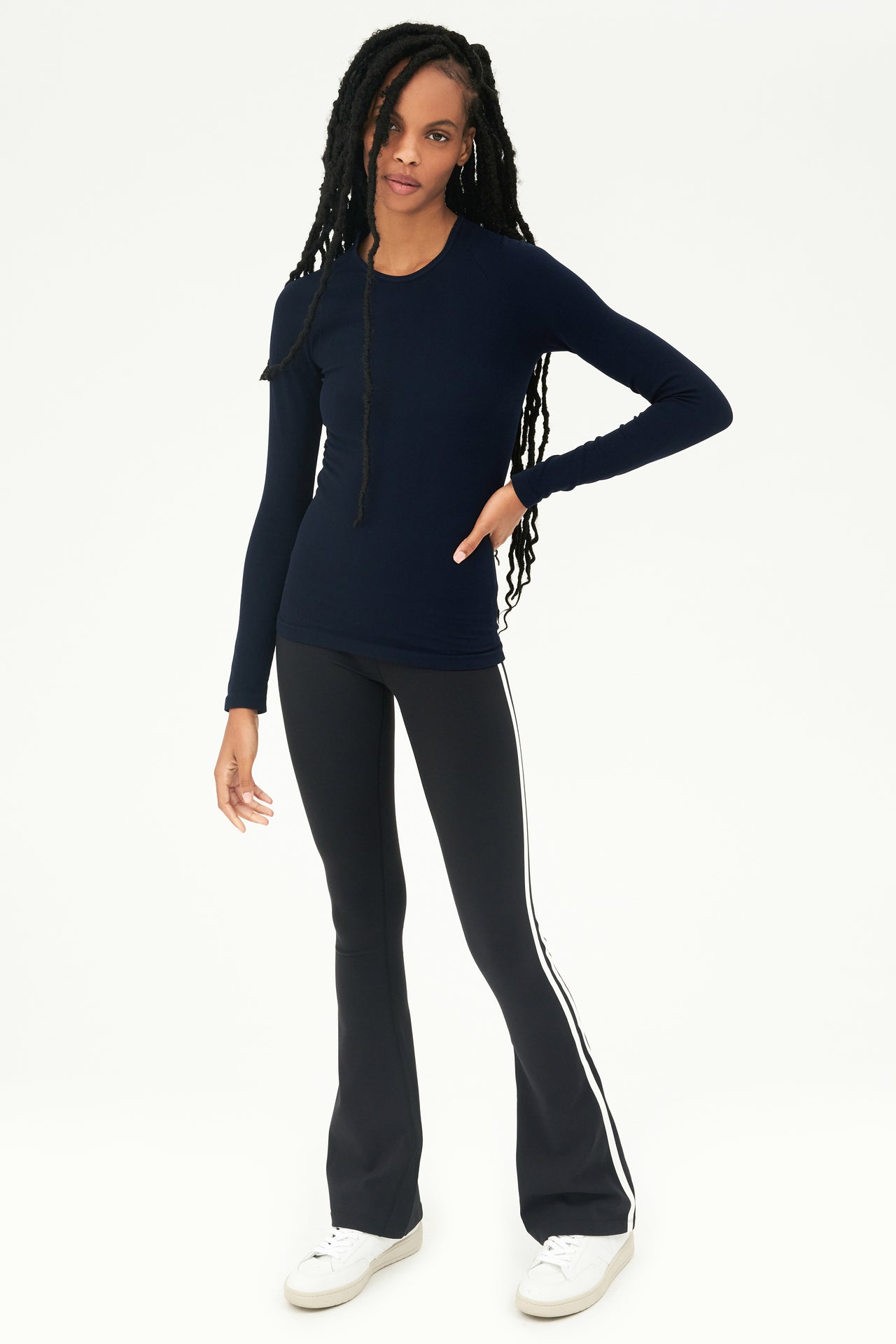 A young woman wearing a SPLITS59 Loren Seamless L/S Tee in Indigo and black leggings designed for gym workouts.