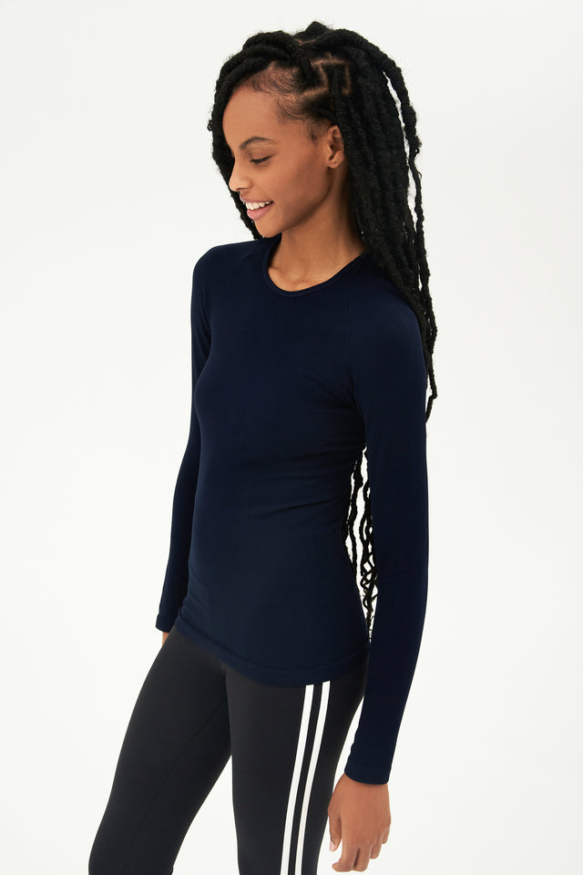 A young woman wearing a SPLITS59 Loren Seamless L/S Tee in Indigo and leggings designed for gym workouts.