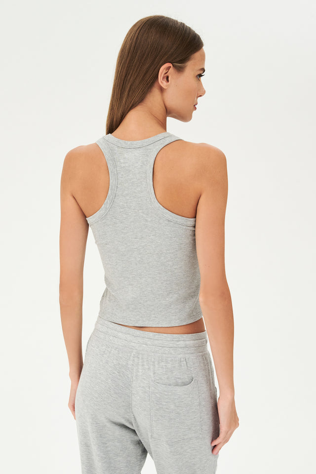 Back view of girl wearing a ribbed grey cropped tank top and grey sweatpants with a white tie along the waistband 