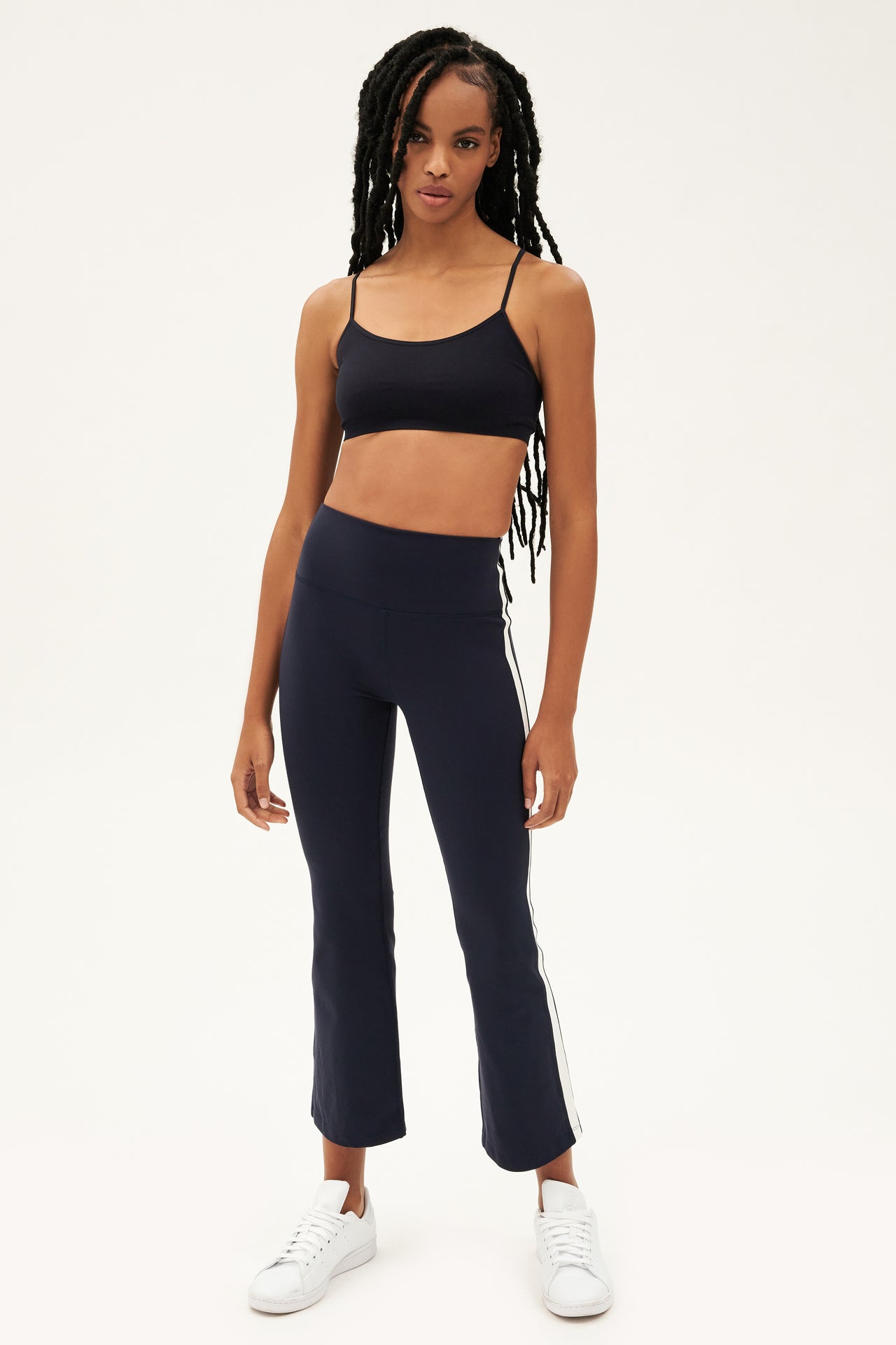 A woman wearing a black crop top and high waist SPLITS59 Raquel navy leggings made from 4-way stretch supplex fabric designed for yoga.