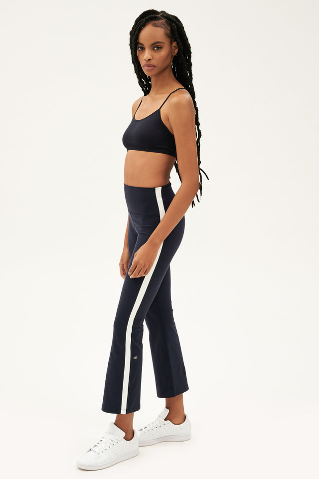 The model is wearing a black and white crop top and Raquel High Waist Crop leggings made of 4-way stretch supplex fabric from SPLITS59.